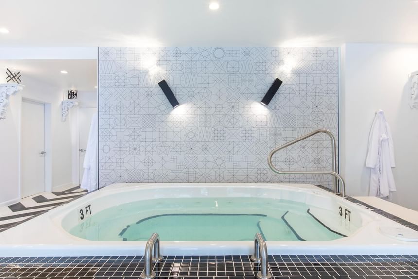 Modern spa room featuring a jacuzzi, geometric tiled wall and lights in The Crooked Cabana at The Roxbury