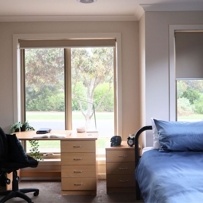 Cozy room with bed, desk, chair, and scenic window view at La Trobe University Regional Housing Melton.