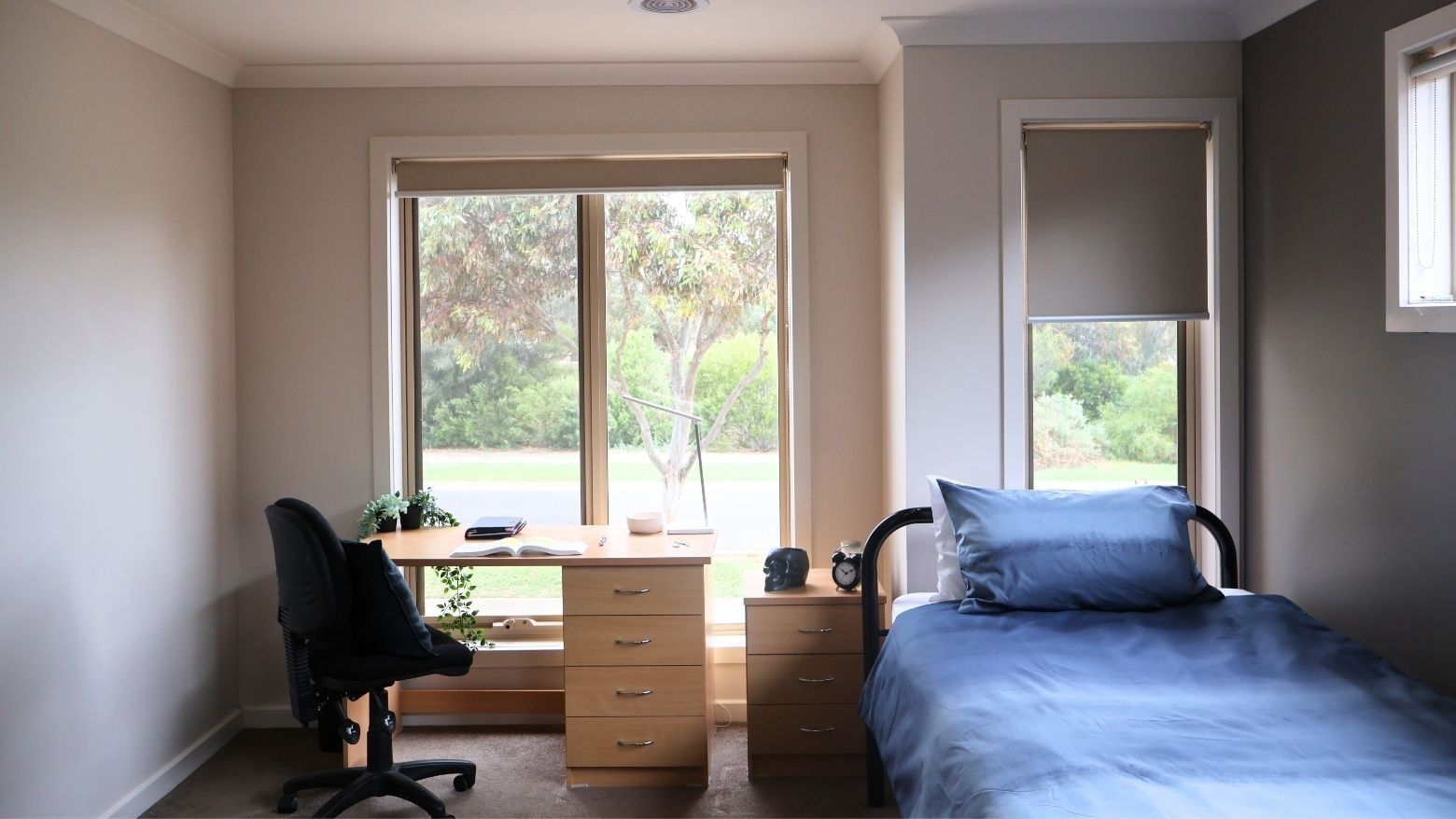 Cozy room with bed, desk, chair, and scenic window view at La Trobe University Regional Housing Melton.