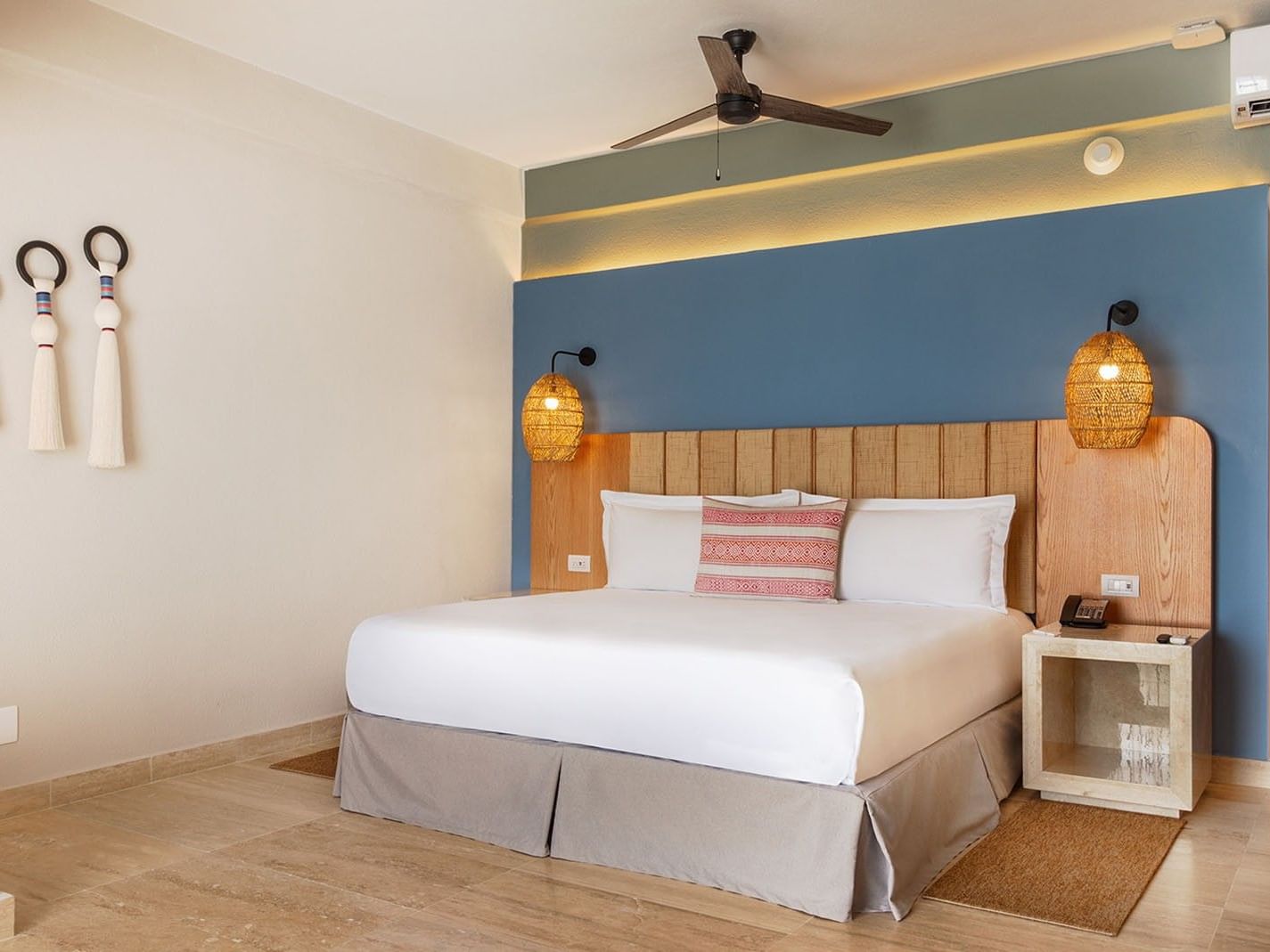 King Camino Real Club king bed with blue accent wall and woven pendant lighting at Camino Real Acapulco Diamante