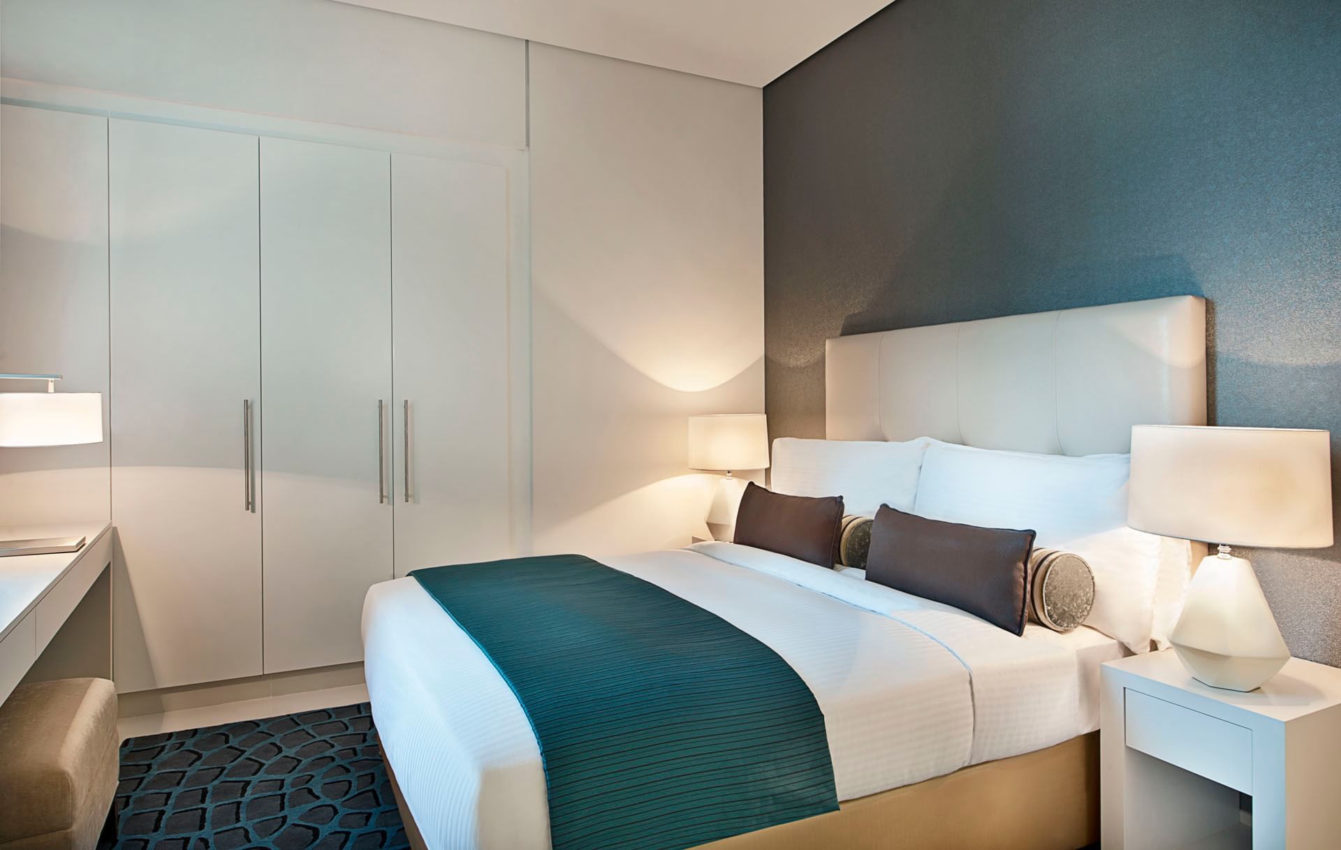 Three Bedroom Suite with a large bed, two lamps, and a wardrobe at DAMAC Maison Cour Jardin Dubai