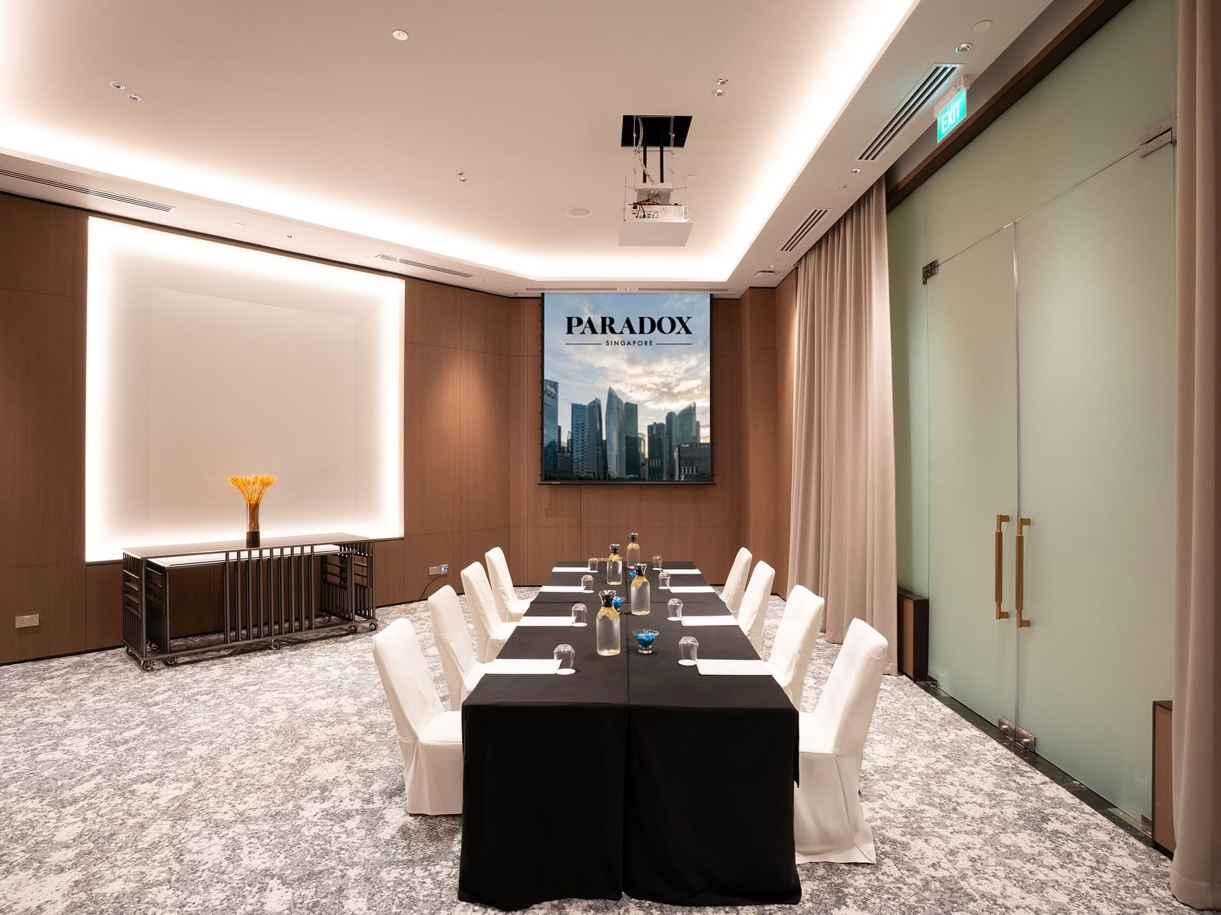 Boardroom setup in a meeting room at Paradox Singapore, with a long rectangular table surrounded by executive chairs, equipped for formal meetings and discussions in a professional environment.