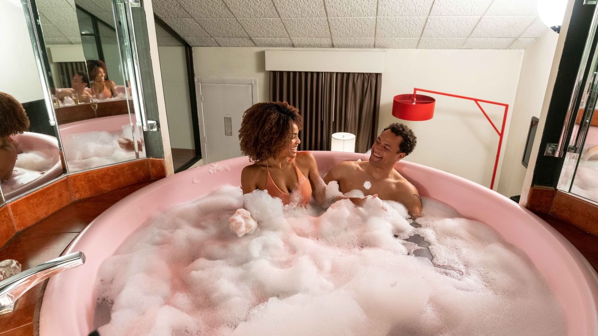 Couple playing with bubbles in the Champagne Tower Suite bathtub at Cove Pocono Resorts