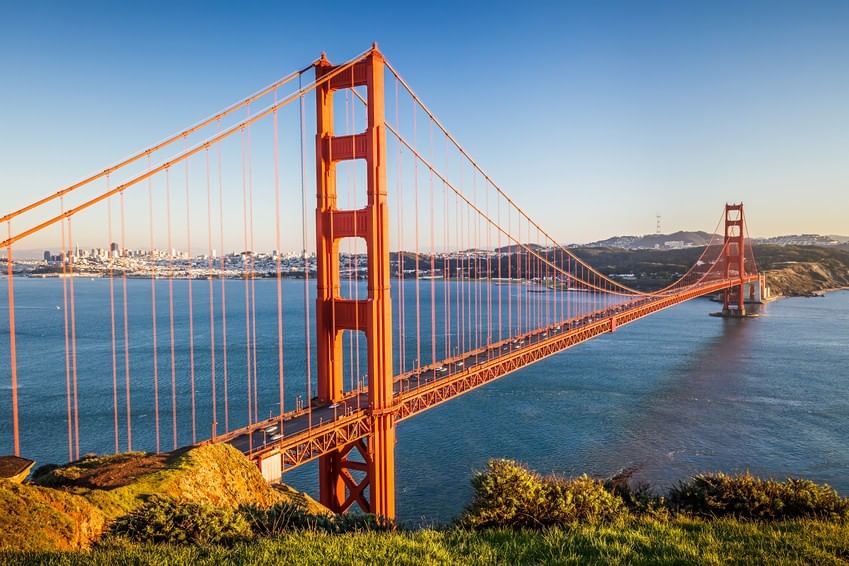 Golden Gate Bridge by a grassy hill under a clear sky near the city bay near Warwick San Francisco