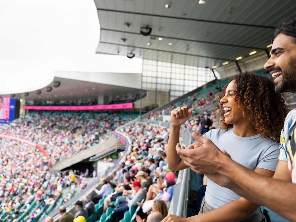 Excited fans cheering in a packed cricket stadium during the Australia v New Zealand Test Series 2027