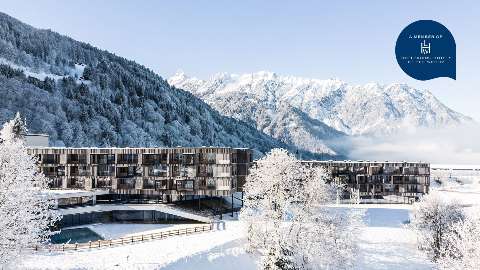 Exterior view of Falkensteiner Hotel Montafon surrounded by snowy forested mountains