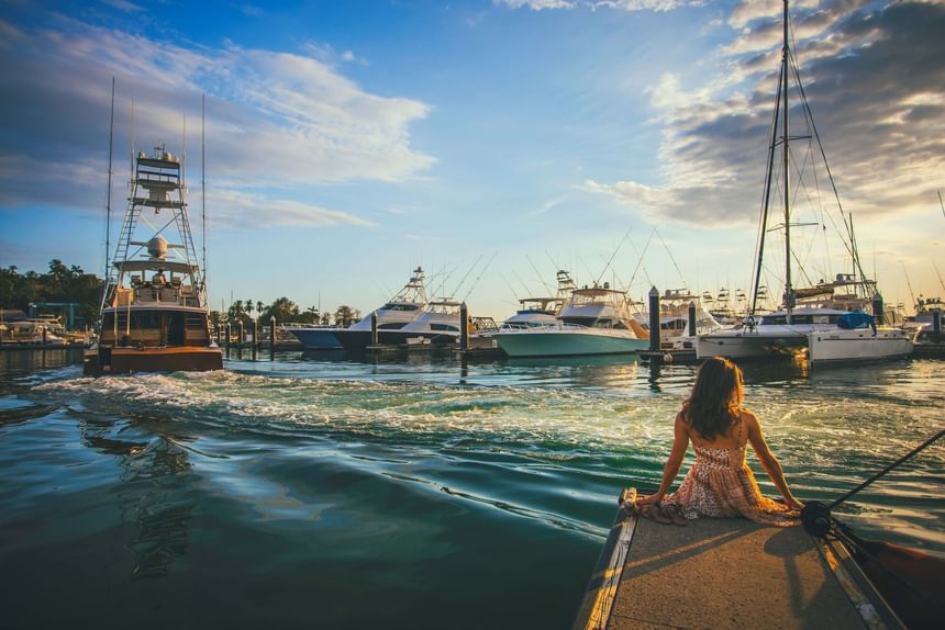 Woman sitting on a dock watching a sport fishing boat leave a harbor at Marina Pez Vela near Jungle Vista Boutique Hotel