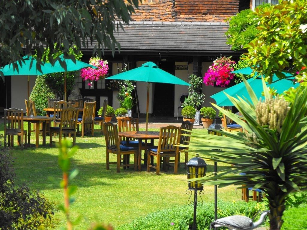 Beautiful outdoor seating at Marygreen Manor, with tables under umbrellas and hanging baskets of flowers on a sunny day