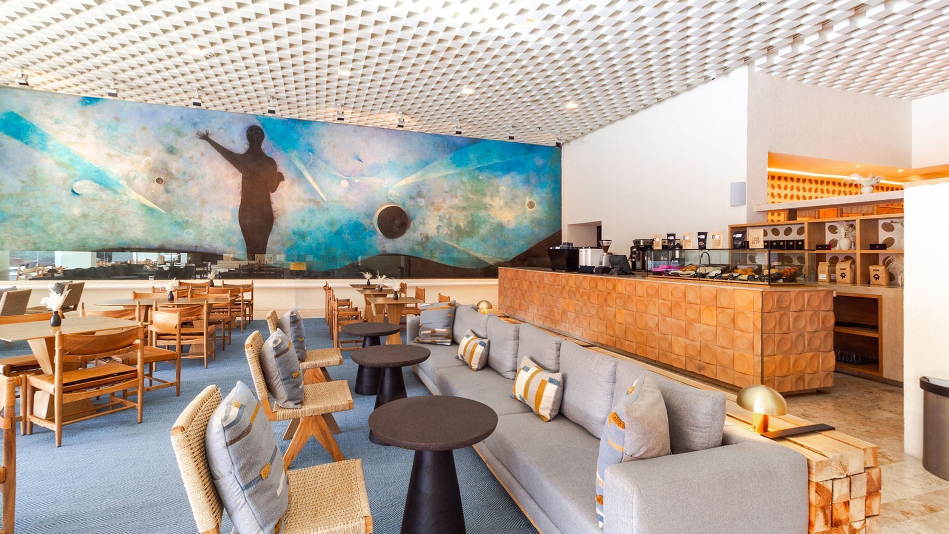 Café Tamayo featuring a large blue mural, grey sofas, and wood accents at Camino Real Polanco Mexico