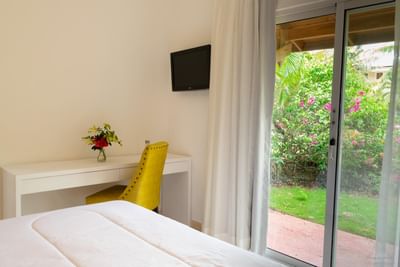Superior Room at La Casita by the Hub, offering a tranquil garden view and a vibrant yellow desk chair