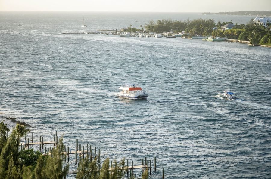 Tour boats by a wooden pier under a hazy sky surrounding a tropical coastline near Warwick Paradise Island Bahamas