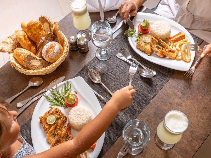 Family enjoying a meal with seafood, rice, and bread at Pickalbatros Sands Hotel in Port Ghalib.