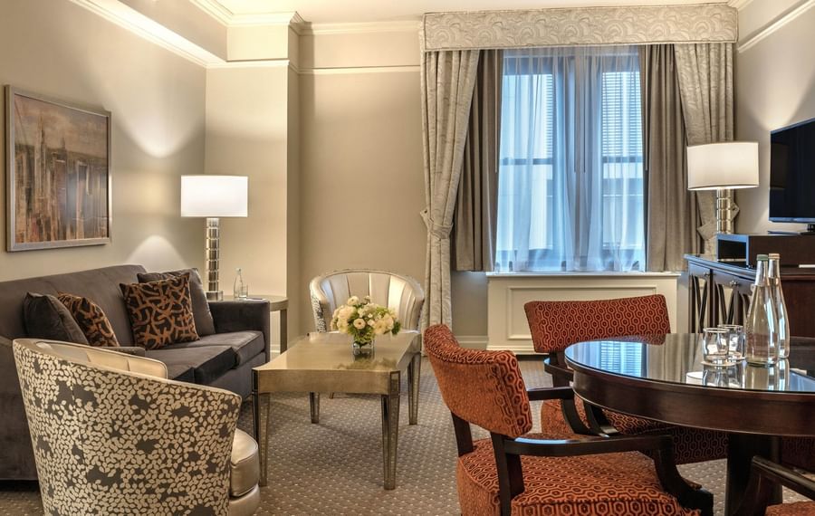 A luxuriously furnished suite with a living area and a glass table at Warwick New York.