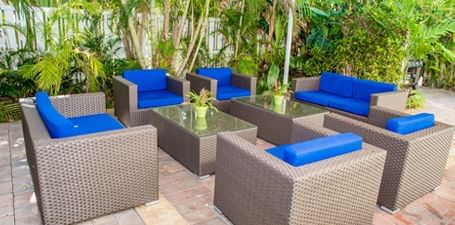 Patio lounge area arranged by a lush green lawn at Ocean Lodge Boca Raton