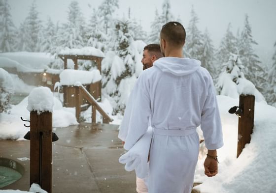 Two men walking into snow-covered Scandinave Spa at Blackcomb Springs Suites