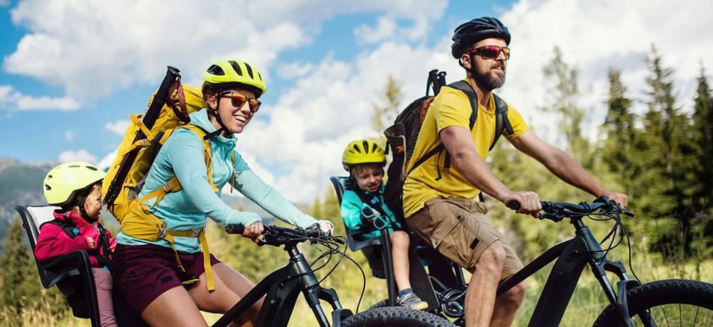 Cyclists riding along a scenic mountain trail in Canmore with the Canadian Rockies in the background.