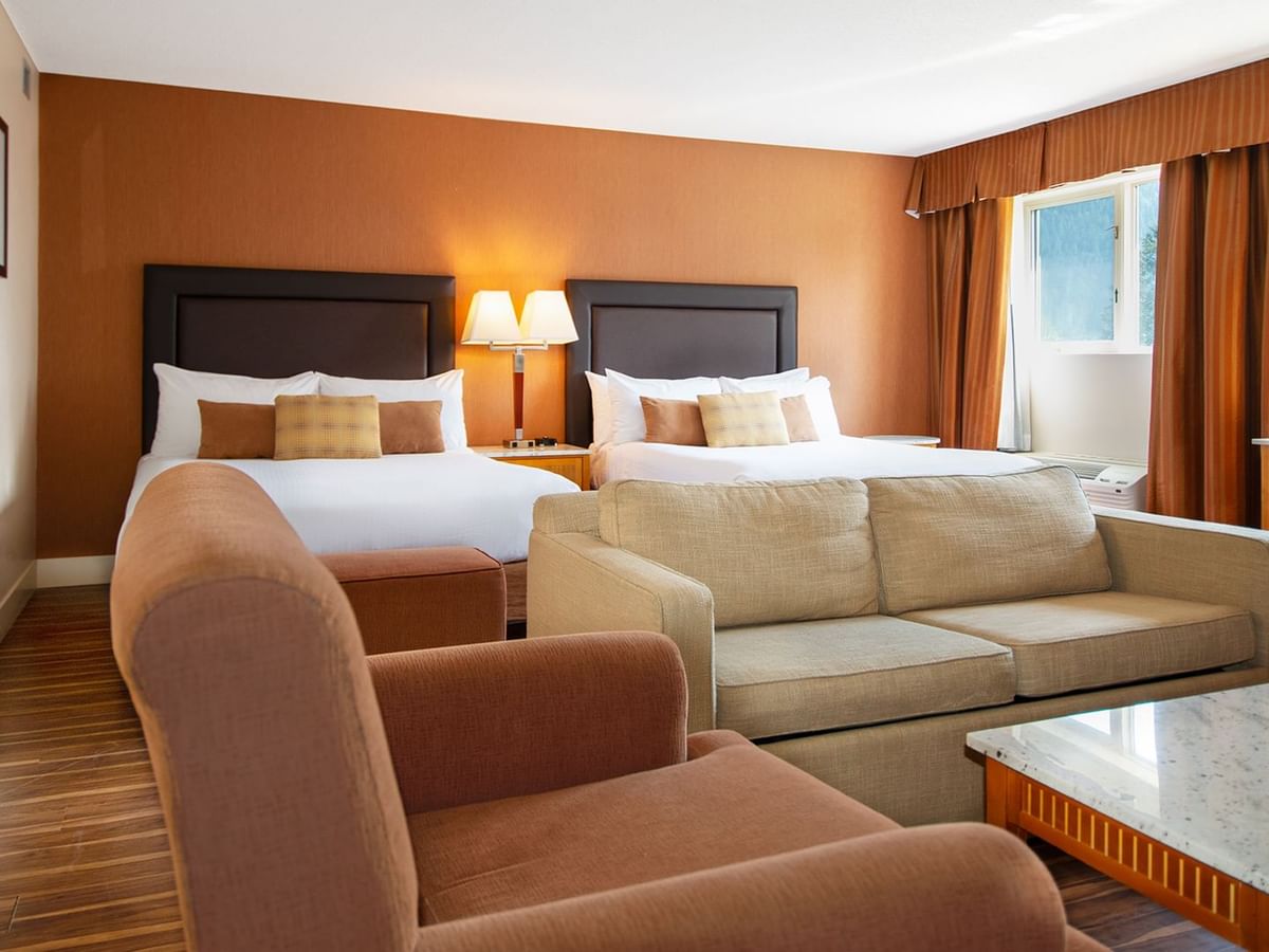 Hotel guest room with two queen beds and arm chairs