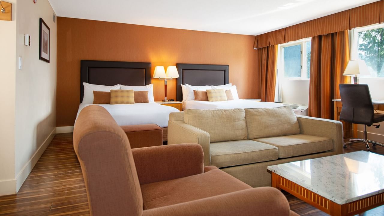 Hotel guest room with two queen beds and arm chairs