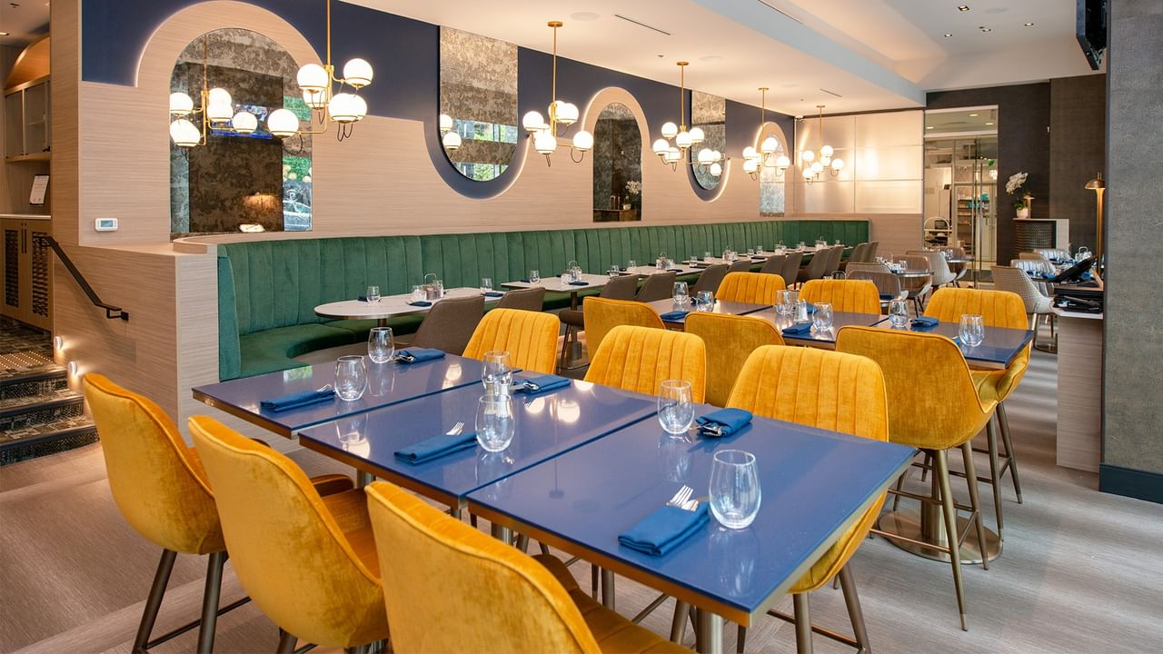 Modern dining space with vibrant yellow chairs, blue tables, and green seating.
