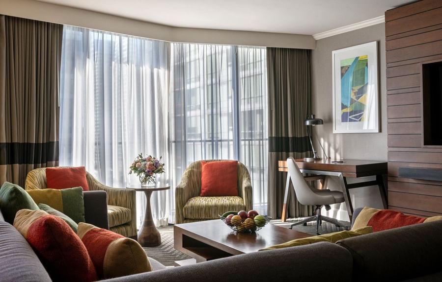 Queen Anne Suite featuring patterned chairs by a wooden desk under large windows at Warwick Seattle