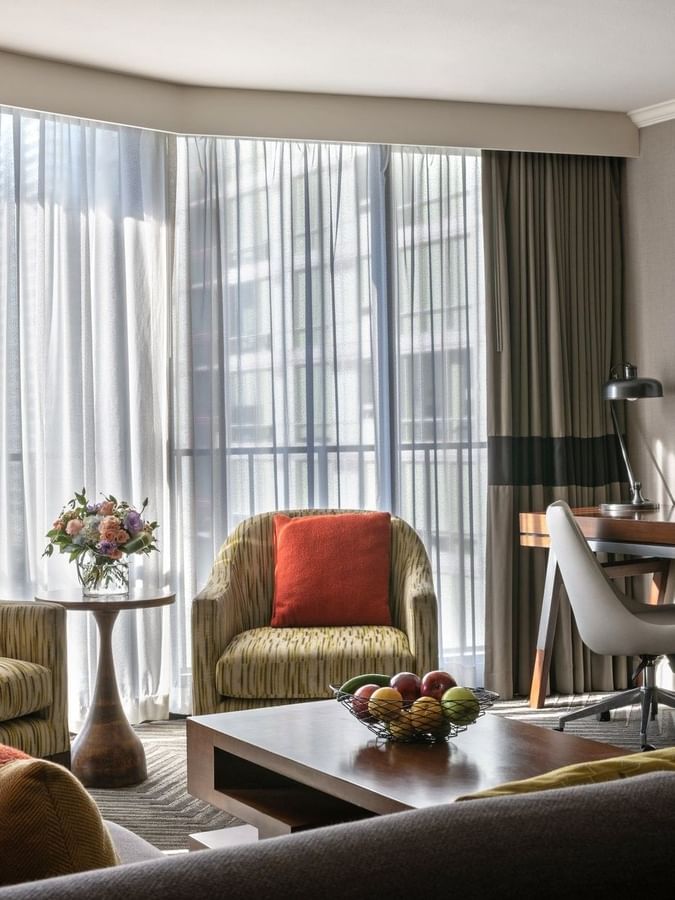 Queen Anne Suite featuring patterned chairs by a wooden desk under large windows at Warwick Seattle