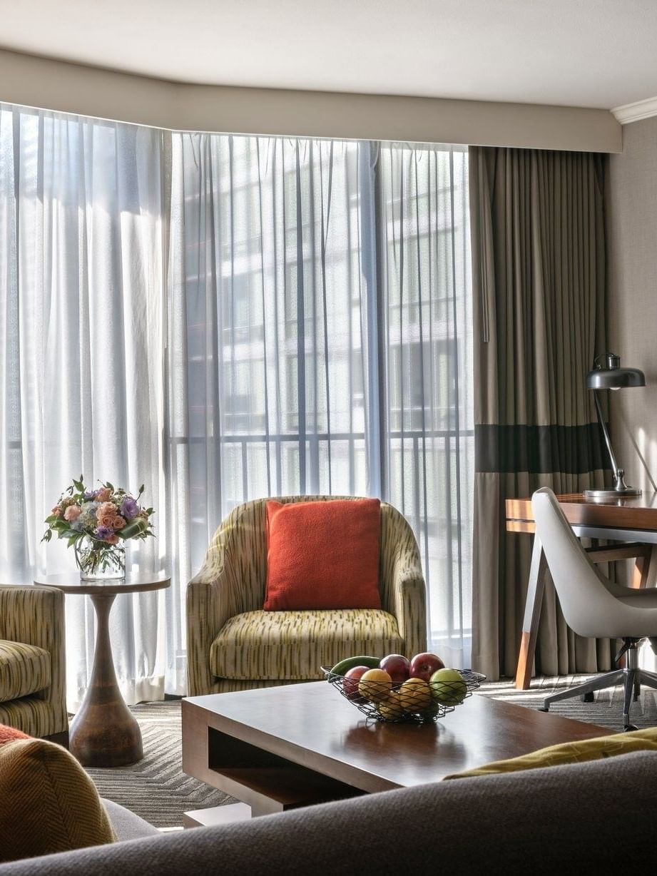 Two armchairs by a round side table near a wooden desk and office chair in Queen Anne Suite (1907) at Warwick Seattle