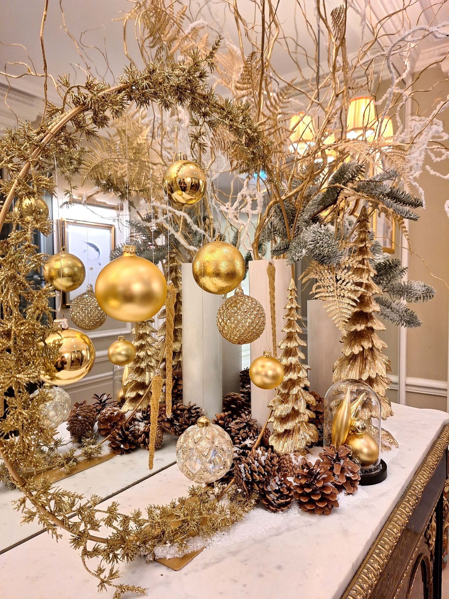 A festive arrangement with gold ornaments, miniature trees, pinecones, and elegant decor at Hôtel Westminster - Paris