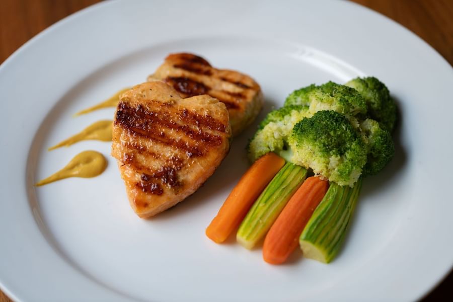 Grilled heart-shaped salmon fillets served alongside steamed broccoli & carrots in Seasons Restaurant at Warwick Hotel Jeddah