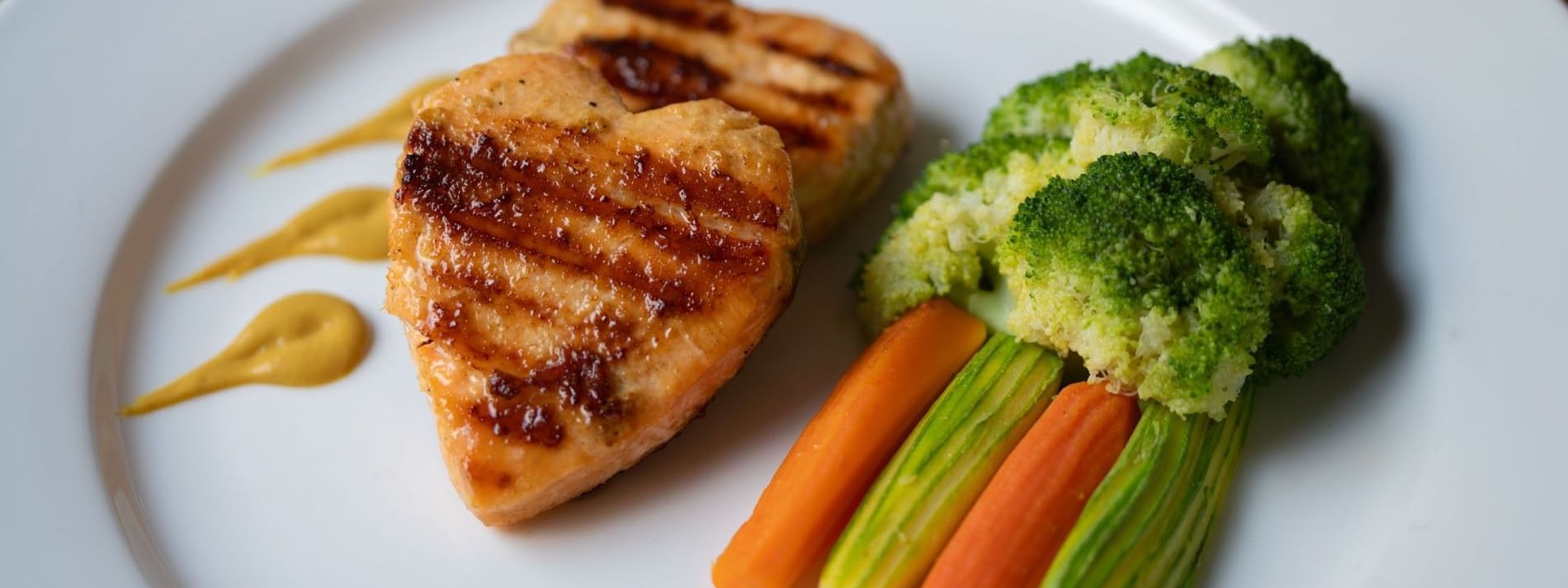 Grilled heart-shaped salmon fillets served alongside steamed broccoli & carrots in Seasons Restaurant at Warwick Hotel Jeddah