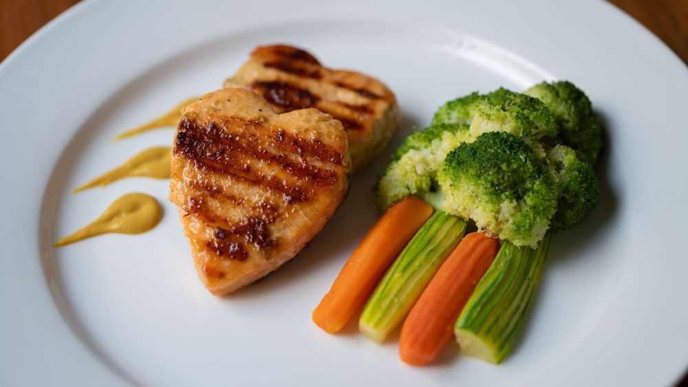 Grilled heart-shaped salmon fillets served alongside steamed broccoli & carrots in Seasons Restaurant at Warwick Hotel Jeddah