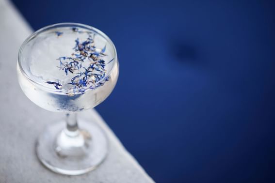 A glass full of cocktail with some blue flakes in it