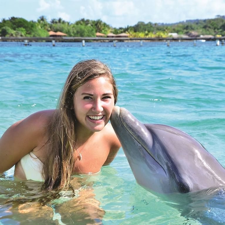 dolphin kissing girl in ocean water