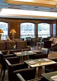 Interior of Randolph\’s Bar & Lounge with leather sofas by granite tables and wooden bar stools under pendant lighting