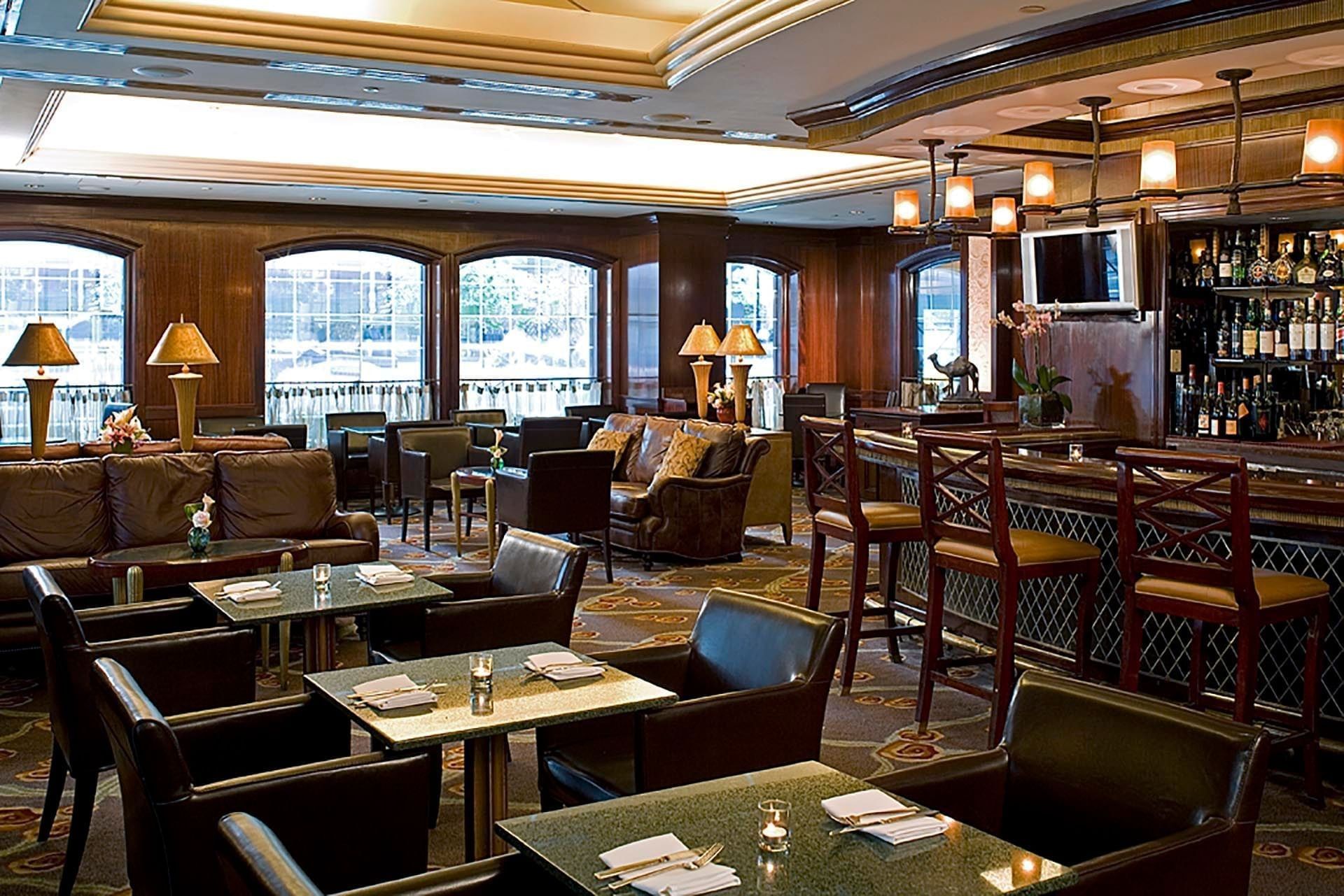 Interior of Randolph\’s Bar & Lounge with leather sofas by granite tables and wooden bar stools under pendant lighting