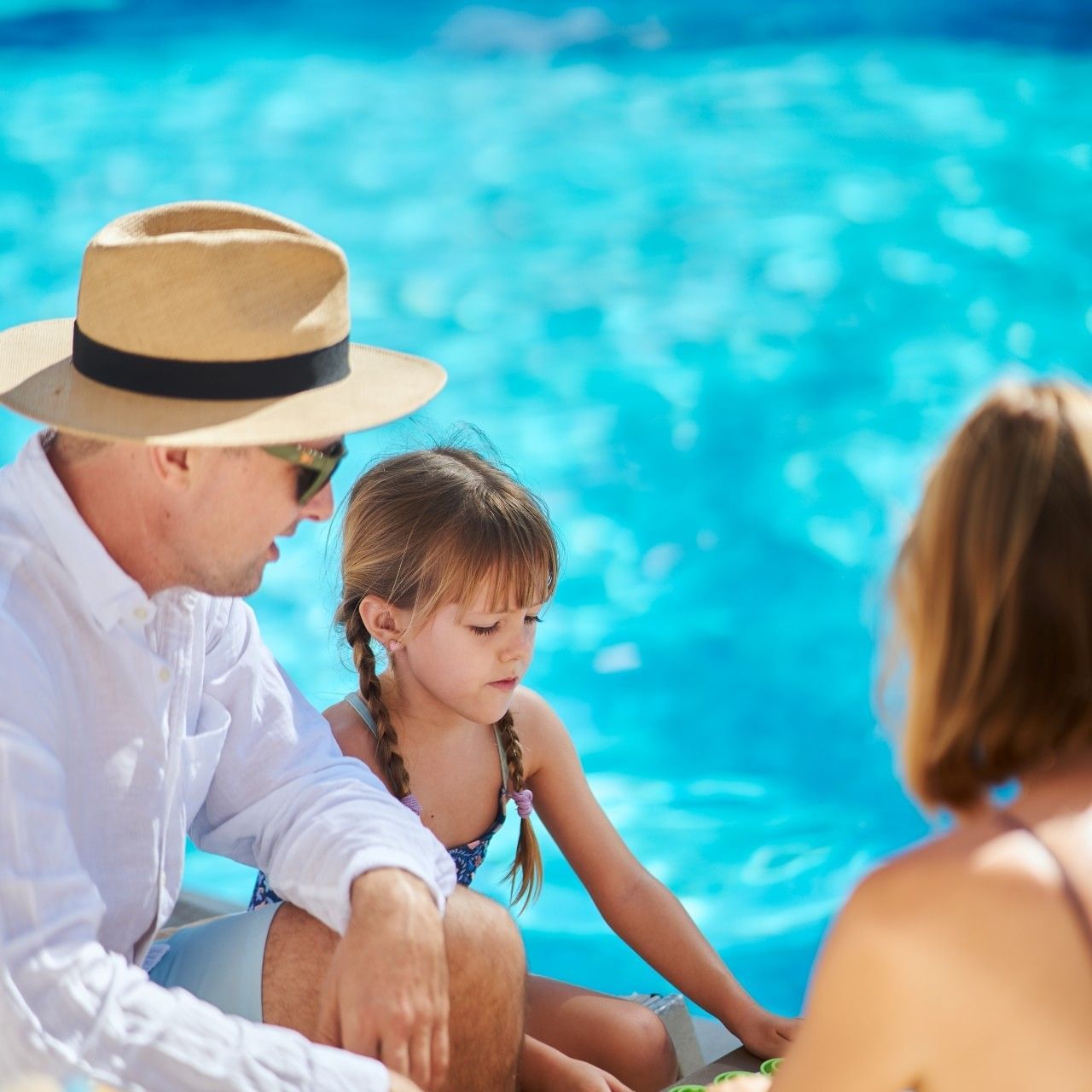 Family enjoying quality time by the pool at Buenaventura Grand Hotel, with a father and two children playing together in a bright beachfront setting.