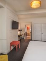 TV facing bed with work desk near the doorway in the Modern Art Suite at Warwick New York