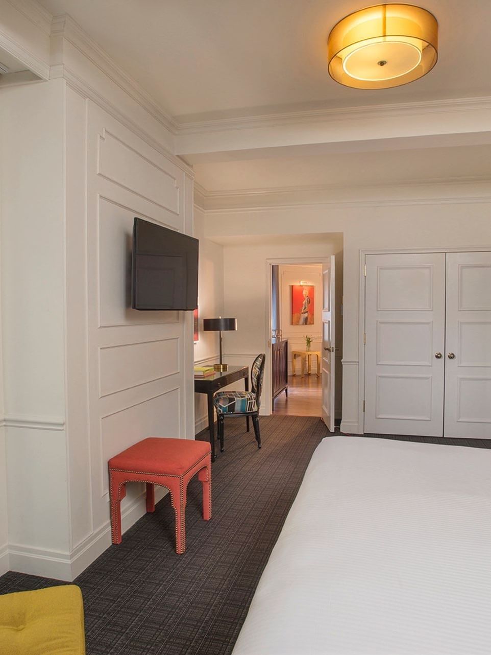 TV facing bed with work desk near the doorway in the Modern Art Suite at Warwick New York