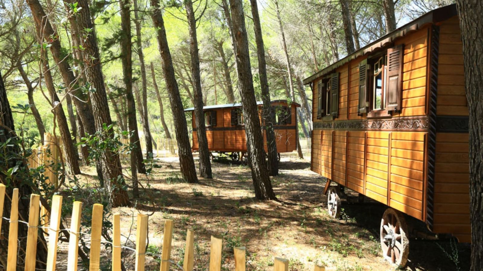 Trailer Cabins in a Forest by a fence at Domaine De Manville