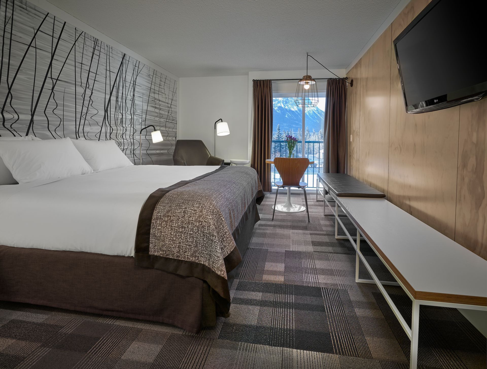 King bed and TV in modern hotel room with mountain views