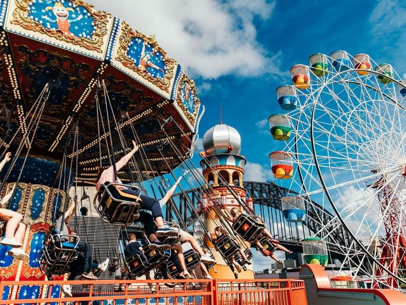 Families enjoying rides at an amusement park under a blue sky, showcasing the Family Getaway offer.