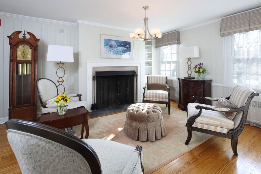 Elegant living room with fireplace, grandfather clock, and striped upholstered chairs at Aramark Chauncey Conference Center