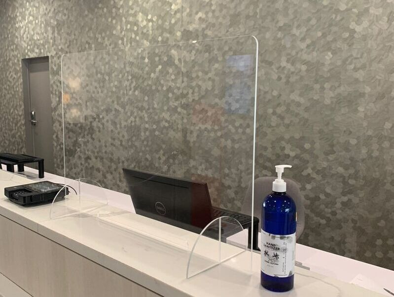 Closeup on the front desk shield & a sanitizer at Anaheim Hotel