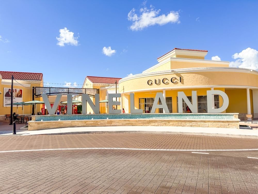 A large sign spelt out "VINELAND" with fountains underneath and a Gucci store in the background.