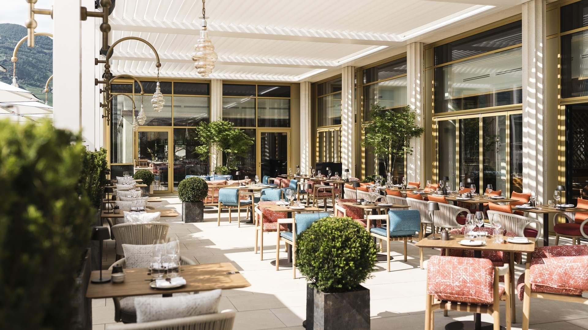 Elegant outdoor restaurant with modern decor, large glass windows, and neatly arranged tables and chairs.