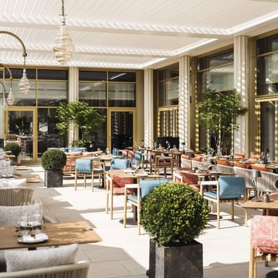 Ristorante esterno con tavoli, sedie, piante, vasi e lampadari in un ambiente elegante e moderno.