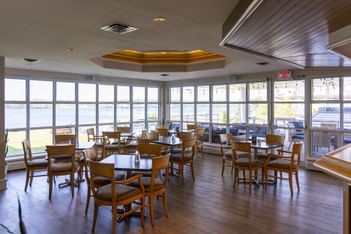 Dining tables in a sunlit room surrounding a lake view at Rodd Brudenell River Resort, one of the Best places to stay in PEI