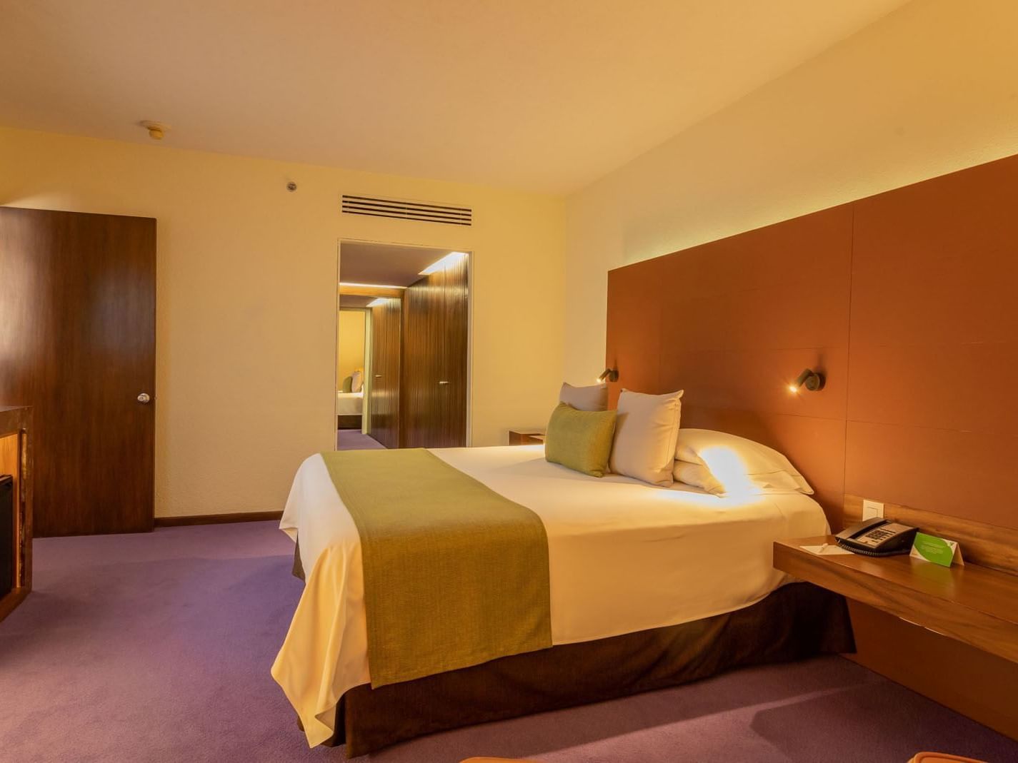 King Junior Suite at Camino Real Polanco Mexico, with a brown headboard, purple carpet, and an open doorway