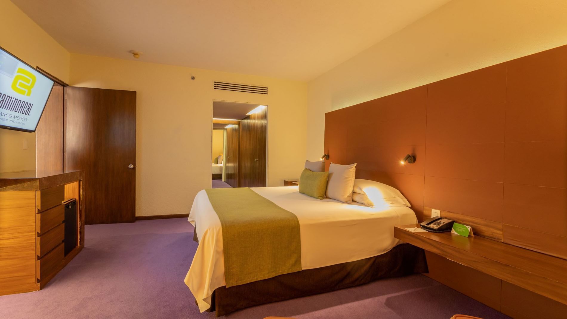 Suite Junior King en Camino Real Polanco México, con cabecera marrón, alfombra púrpura y una puerta abierta