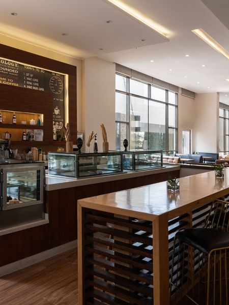 Artist Lobby Lounge with warm wood tones, high seating, and large windows at Warwick Hotel Jeddah