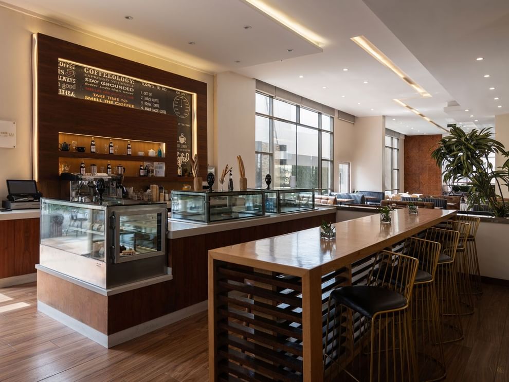 Artist Lobby Lounge with warm wood tones, high seating, and large windows at Warwick Hotel Jeddah